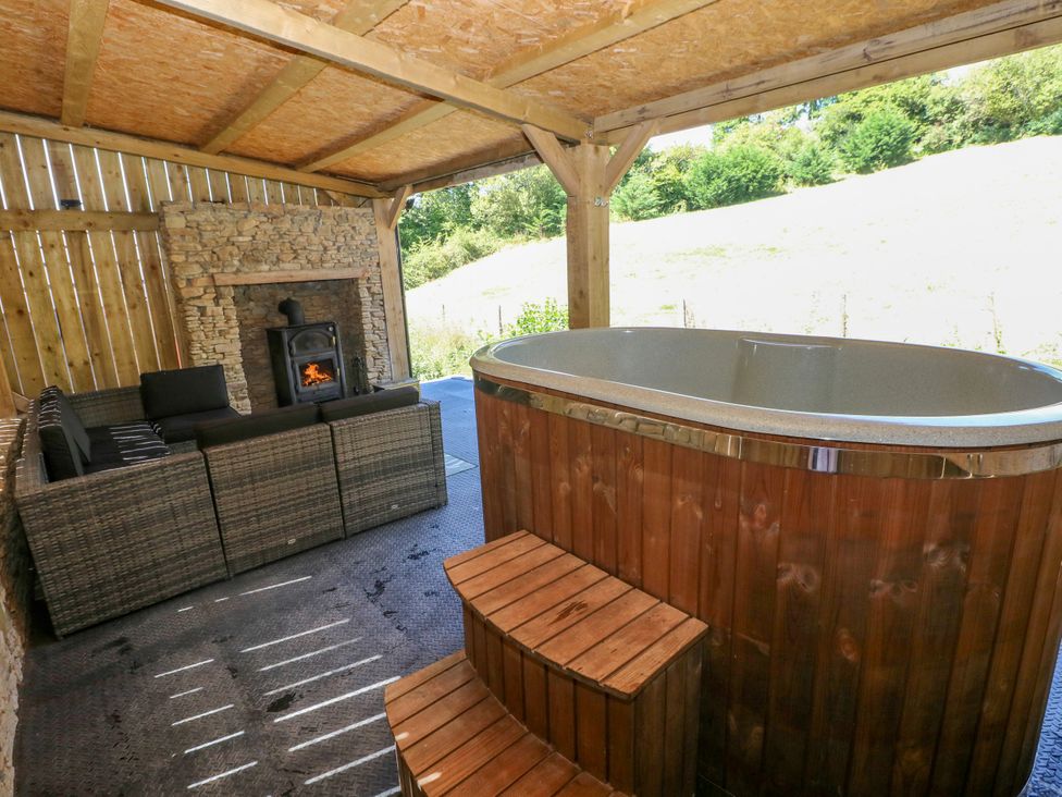 An outdoor seating area with a hot tub and sofa at Thelma’s Lodge near Pontyates