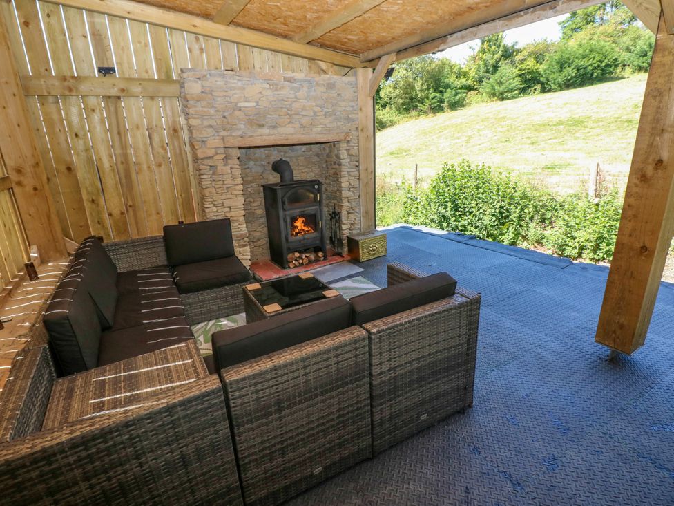 An outdoor seating area with a fireplace and sofa at Thelma’s Lodge near Pontyates