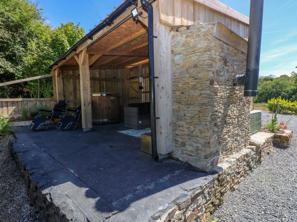 An outdoor space with a hot tub and chairs at Thelma’s Lodge near Pontyates