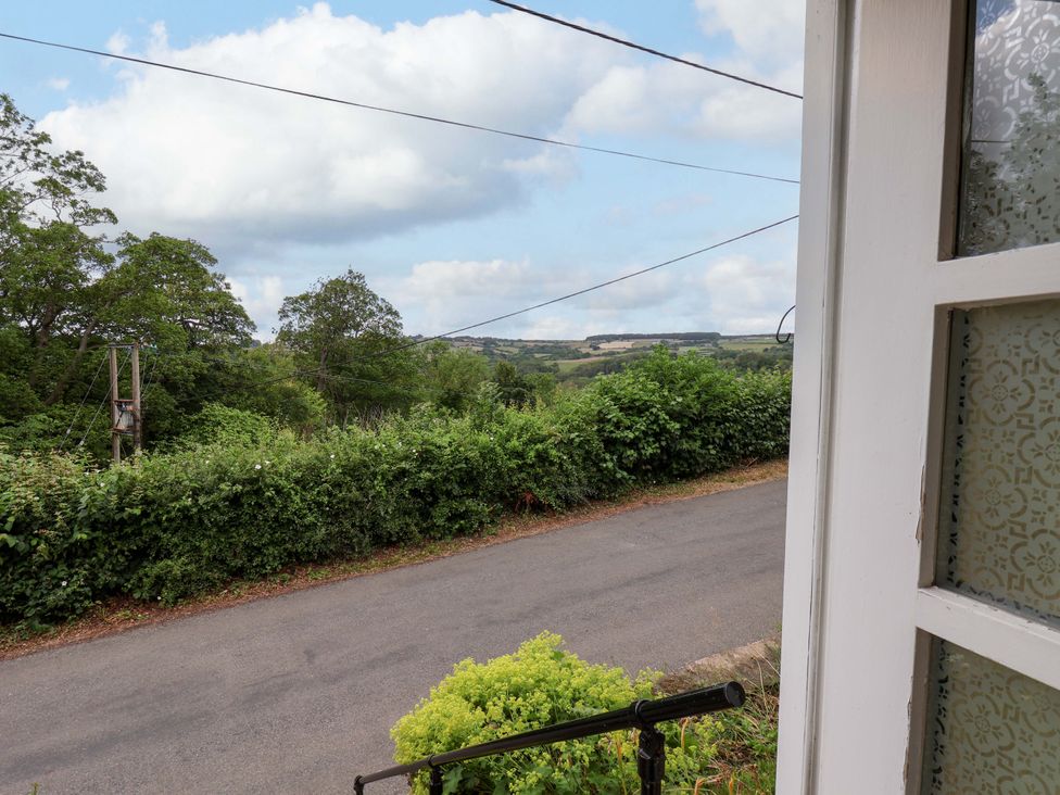 A view from a property showing a road, trees, and fields at 5 Hollins Cottages in Whitby