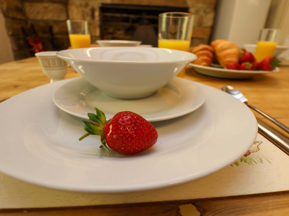 A dining table set with a bowl, plates, glasses, and croissants at 5 Hollins Cottages, Whitby