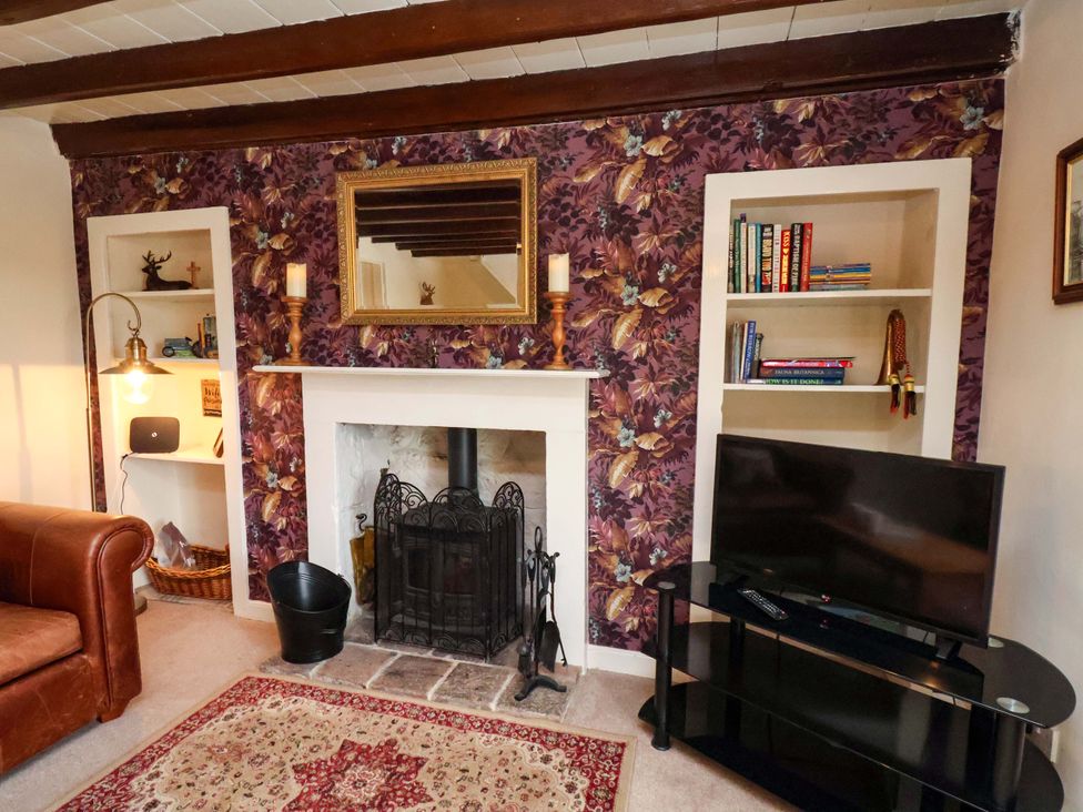 A living room with a fireplace and shelves at 5 Hollins Cottages in Whitby
