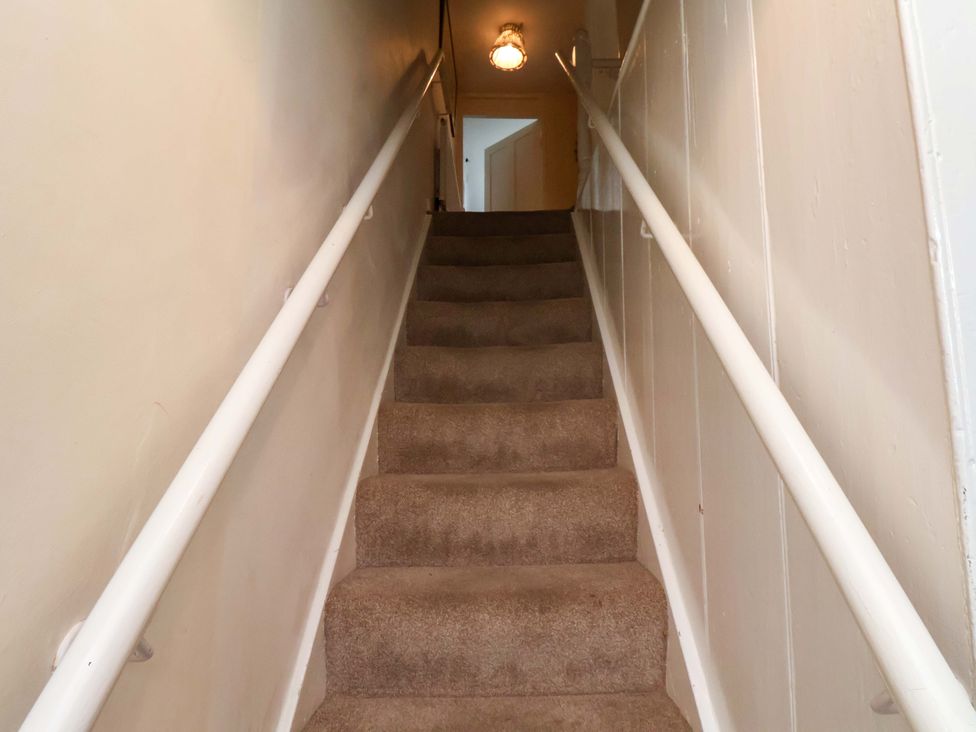 A staircase with a handrail and light fixture at 5 Hollins Cottages in Whitby