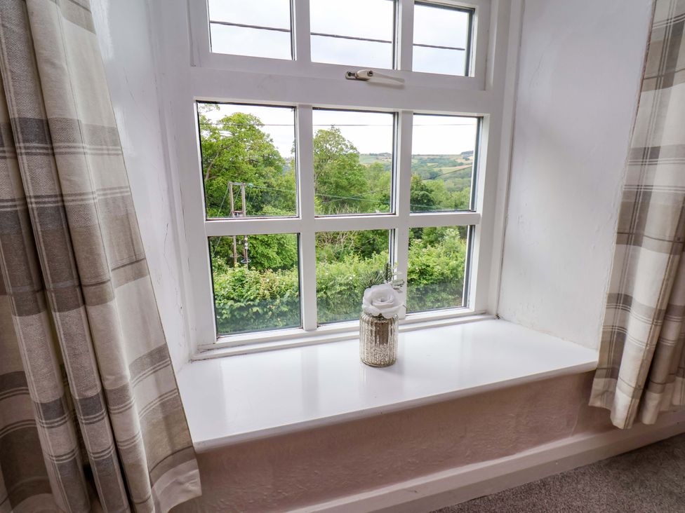 A window with a flower vase and curtains at 5 Hollins Cottages in Whitby