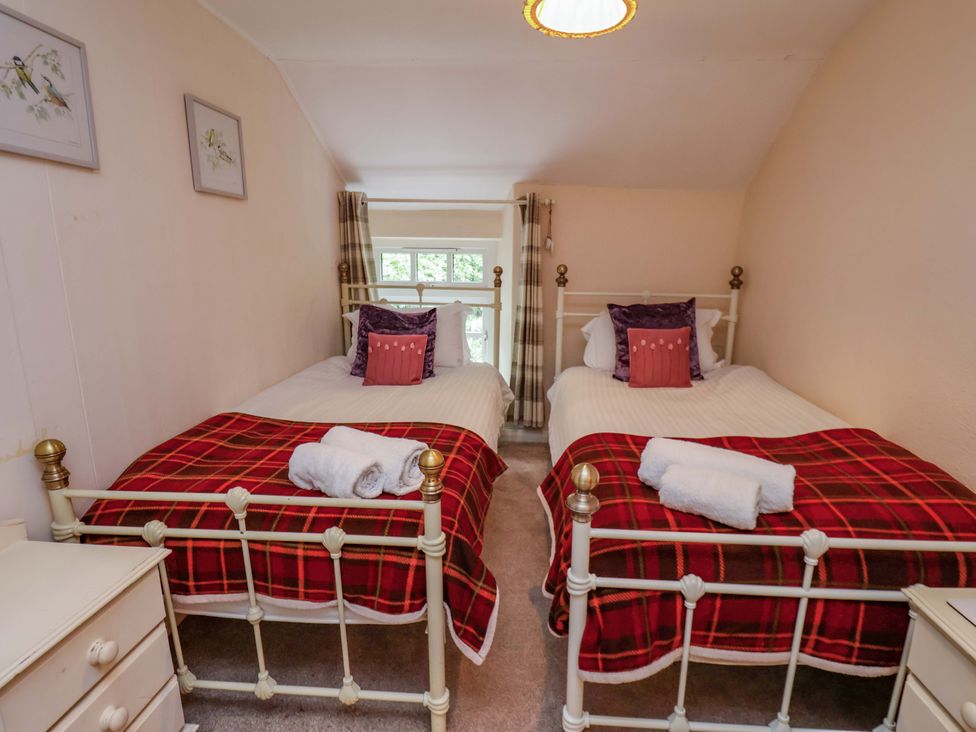 A bedroom with two beds and a window at 5 Hollins Cottages in Whitby