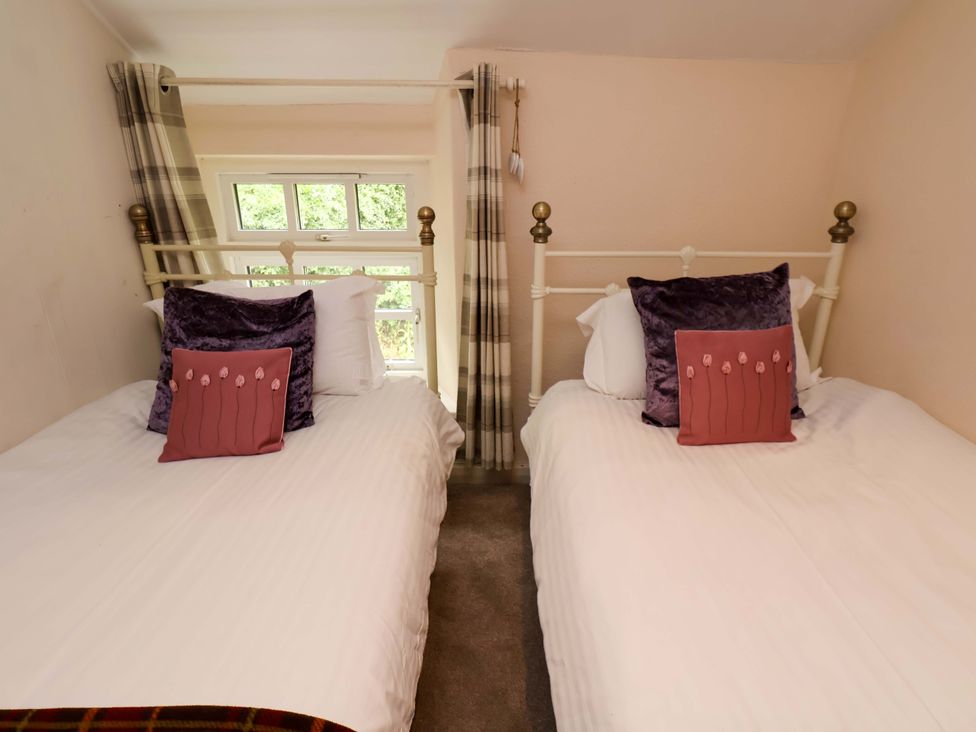 A bedroom with two beds and windows at 5 Hollins Cottages in Whitby
