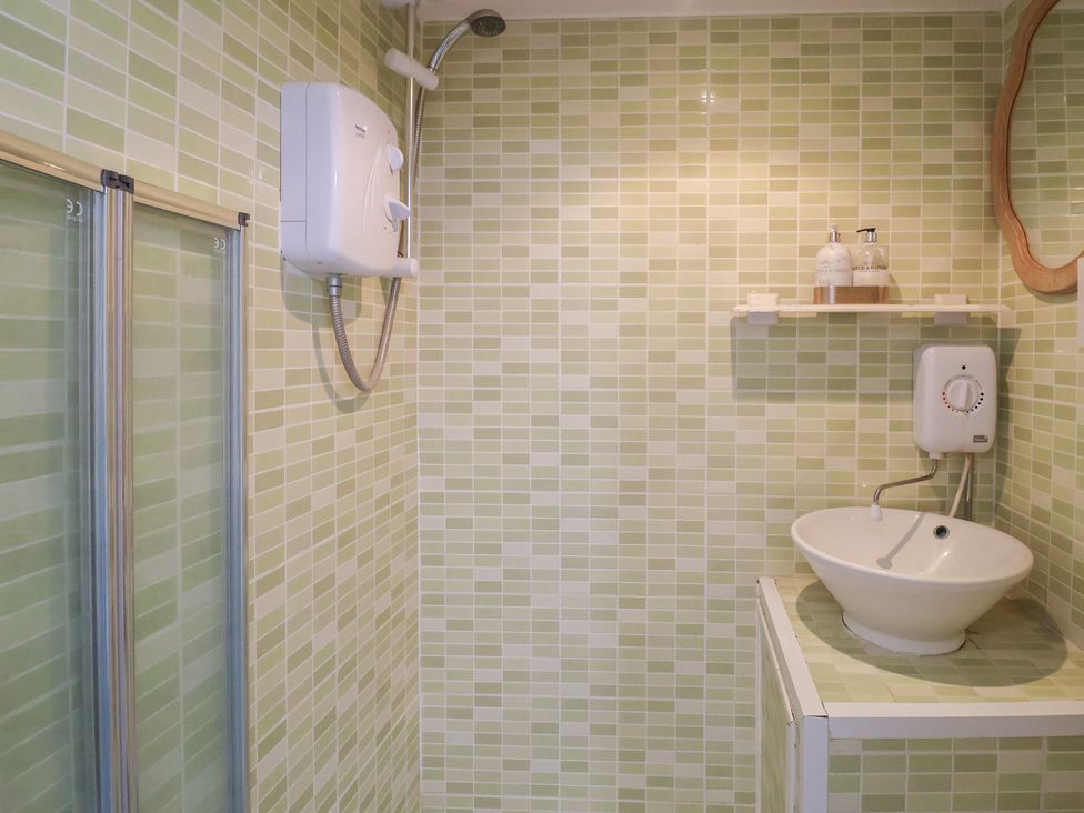 A bathroom with a shower and washbasin at Pebble in Blakeney, Norfolk
