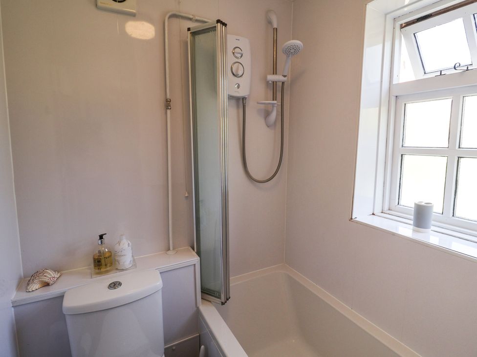 A bathroom with a shower and bathtub at Pebble, Blakeney, Norfolk