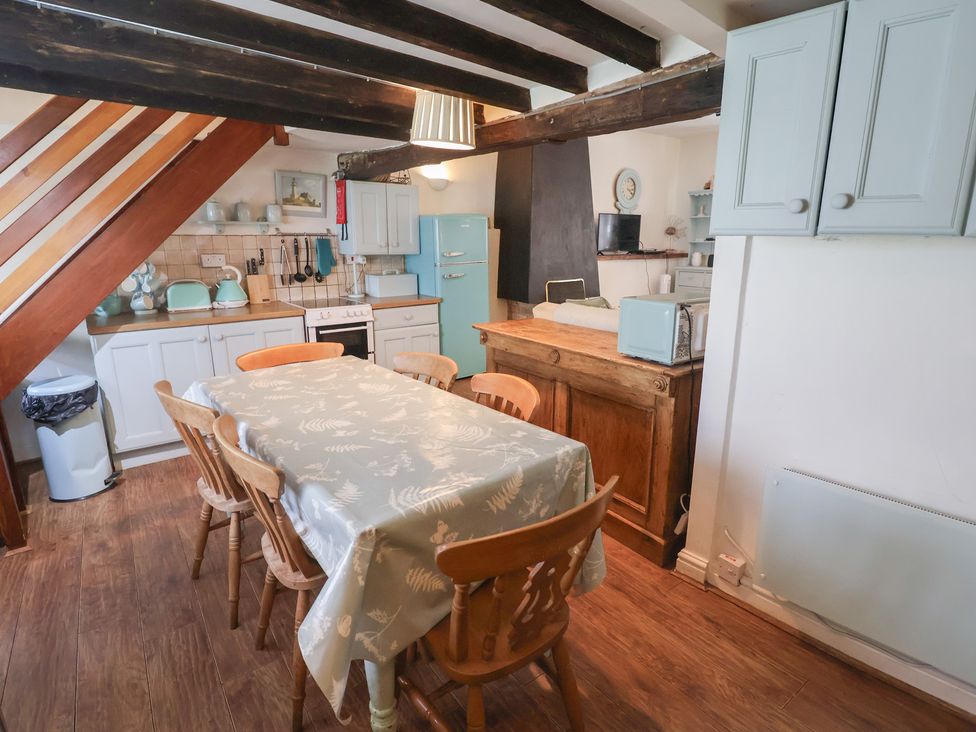 A kitchen with a dining table and cooking appliances at Buttercup in Blakeney, Norfolk