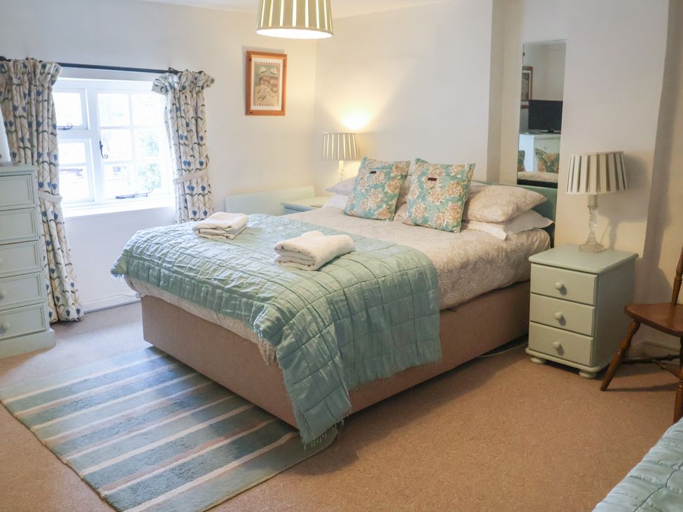A bedroom with bed and bedside table at Buttercup in Blakeney, Norfolk