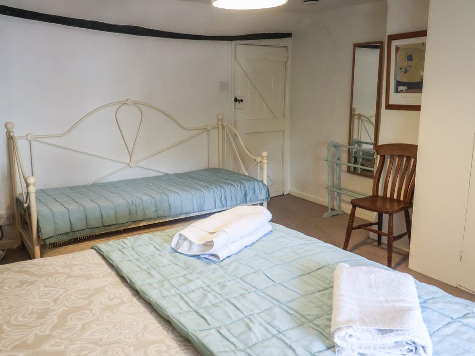 A bedroom with two beds and a chair at Buttercup in Blakeney, Norfolk