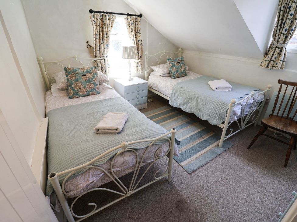 A bedroom with two beds and a bedside table at Buttercup in Blakeney, Norfolk