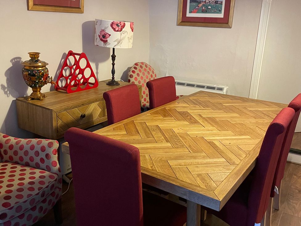 A dining room with a wooden table and red chairs at The Bittern in Blakeney, Norfolk