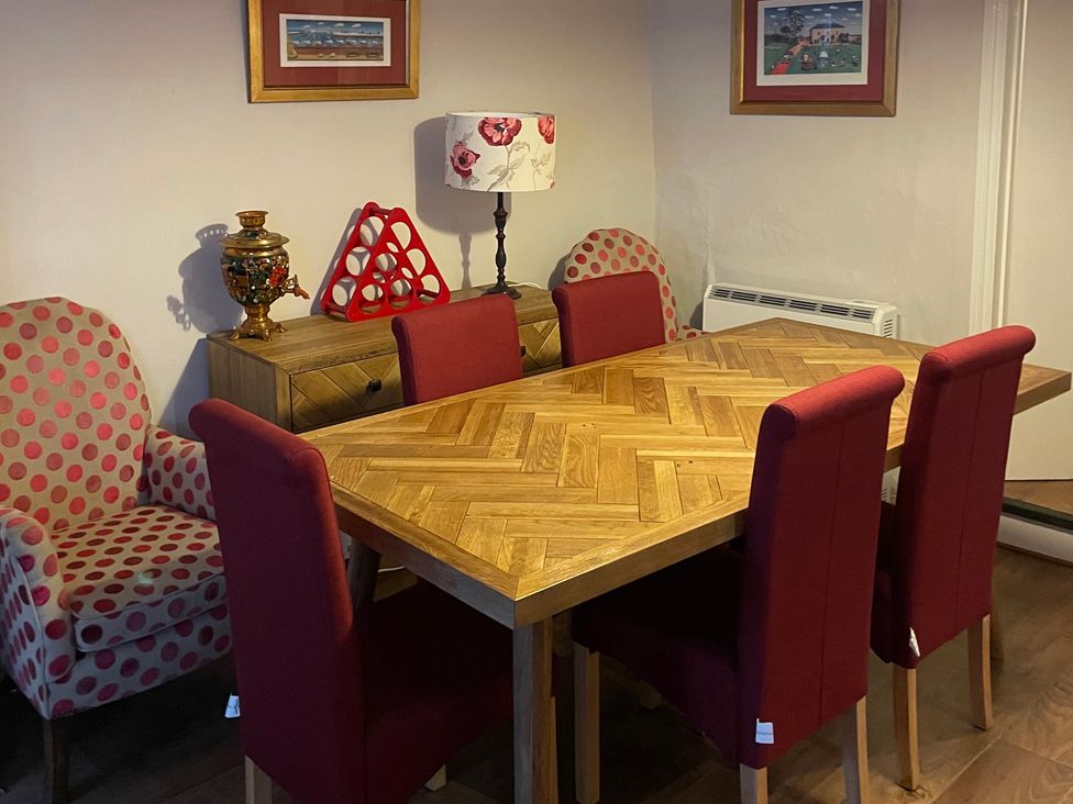A dining room with a wooden table and red chairs at The Bittern in Blakeney, Norfolk