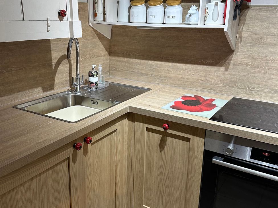 A kitchen with a sink, stove, and storage jars at The Bittern in Blakeney, Norfolk