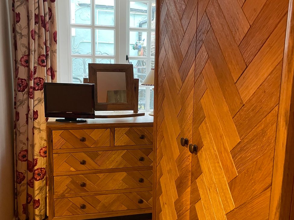 A bedroom with a wardrobe, dresser, television, and mirror at The Bittern in Blakeney, Norfolk