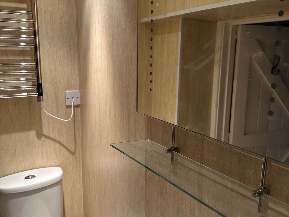 A bathroom with toilet, mirror and shelf at The Bittern in Blakeney, Norfolk