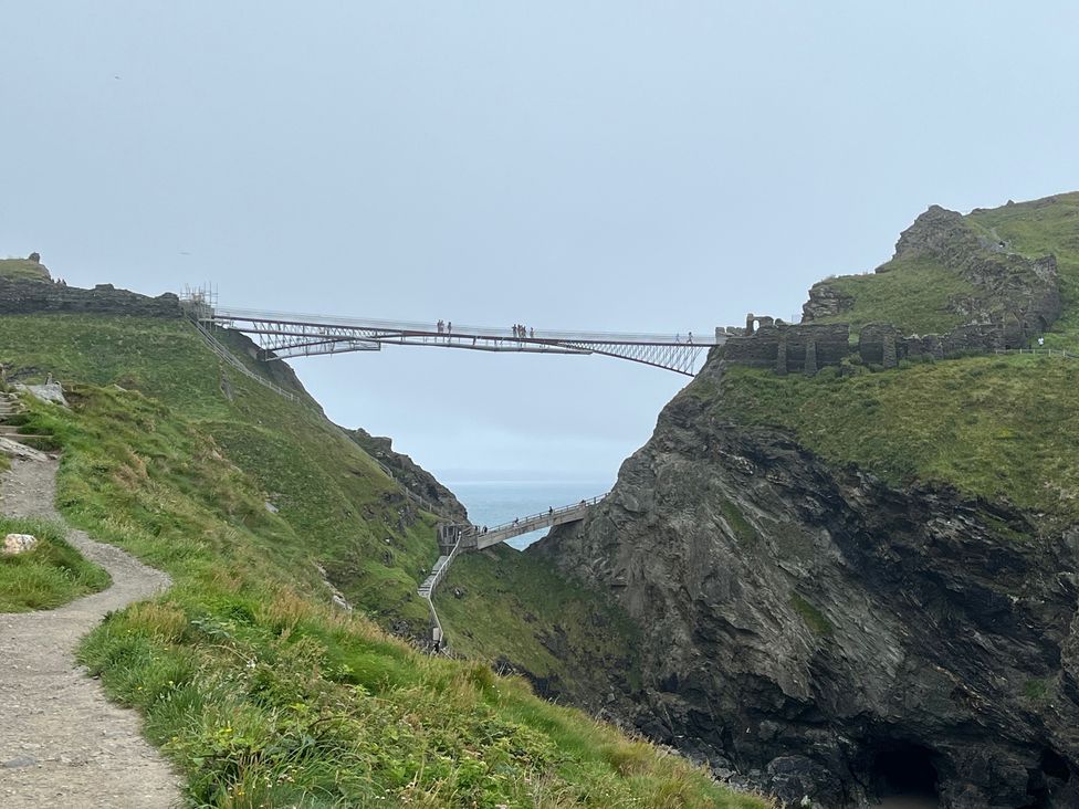 A bridge connecting cliffs over a path and ocean at The Hideaway in Tintagel
