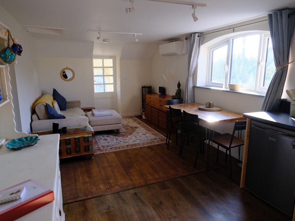 A living room with a sofa and dining table at The Hideaway in Tintagel