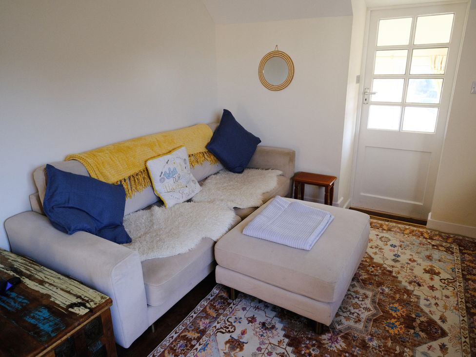 A living room with a sofa, pillows and a side table at The Hideaway in Tintagel