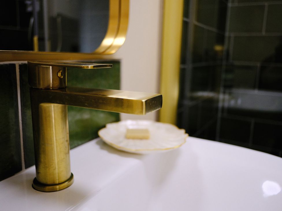 A sink with a gold faucet and a soap dish in a bathroom at The Hideaway in Tintagel