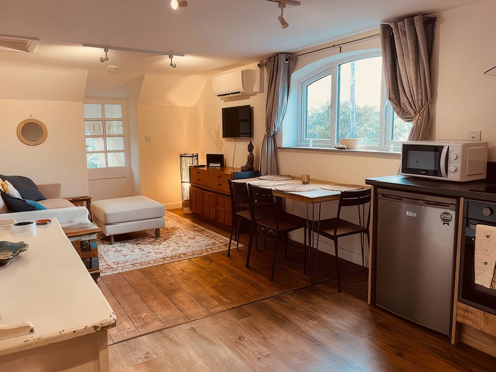 A living room with a sofa and dining area at The Hideaway in Tintagel