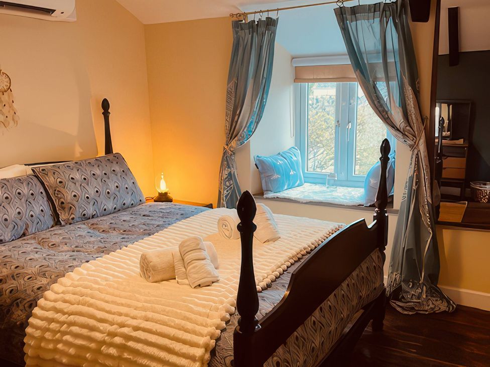 A bedroom with a bed and window at The Hideaway in Tintagel