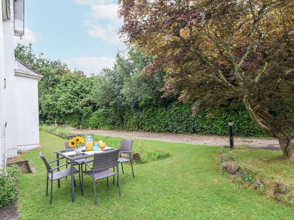 A garden with a table and chairs and a tree at Beach Hideaway