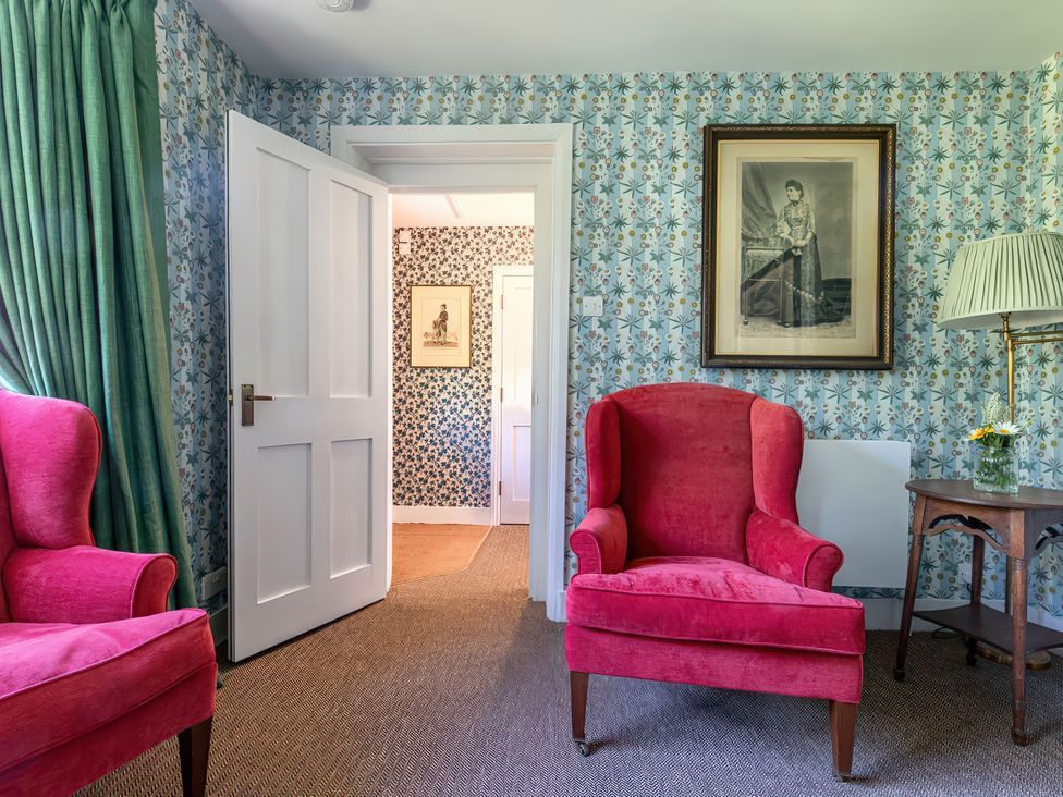 A living room with red armchairs and a table at Dairy Cottage Waddeston