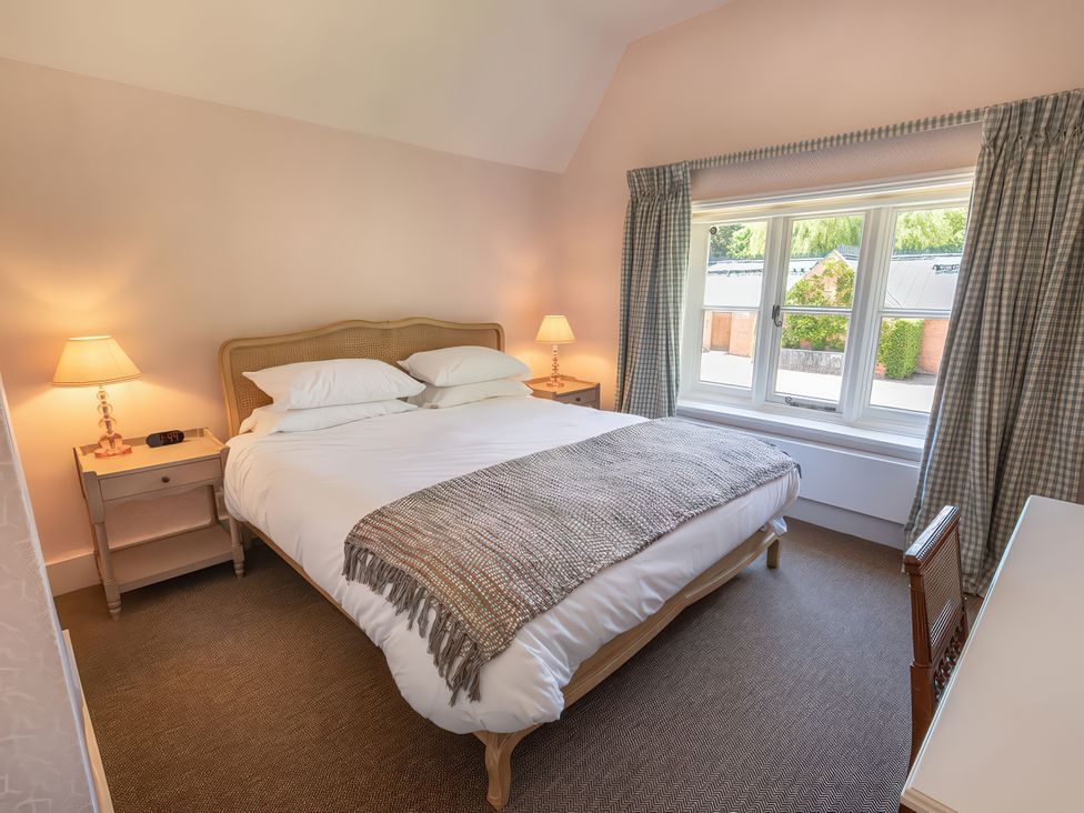 A bedroom with a bed and nightstand at Dairy Cottage in Waddeston
