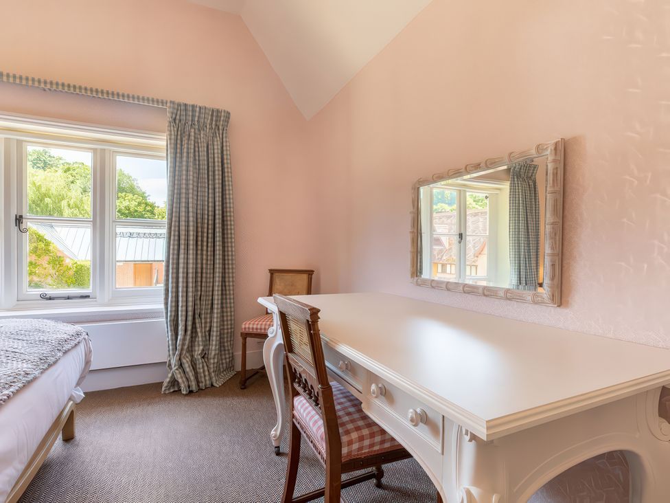 A bedroom with a desk and a mirror at Dairy Cottage in Waddeston