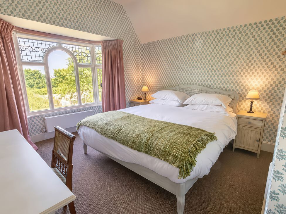 A bedroom with a bed, desk, and lamp at Dairy Cottage in Waddeston