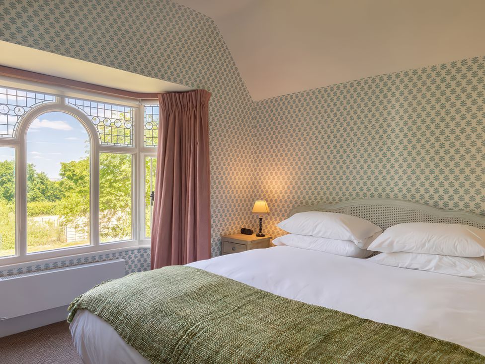A bedroom with a bed and window at Dairy Cottage in Waddeston