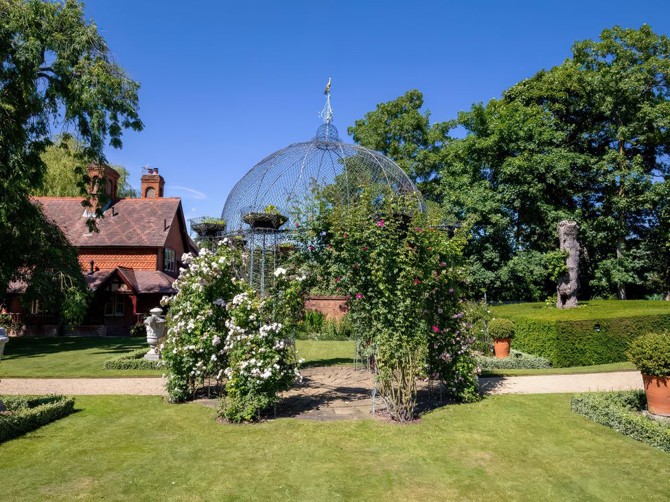 A garden with a metal structure and flowers at Dairy Cottage in Waddeston