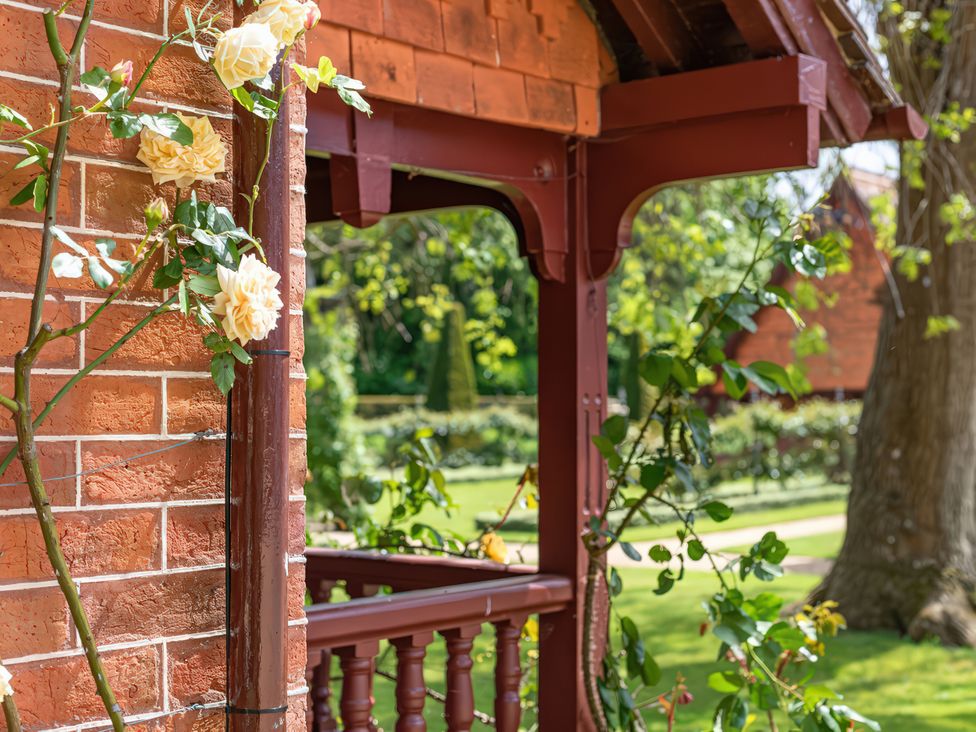 A corner of a garden structure with roses at Dairy Cottage in Waddeston