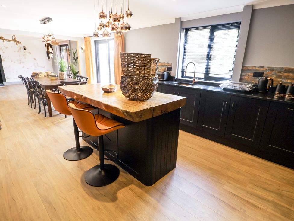A kitchen with a bar island and dining table at Holly Farm in Colchester