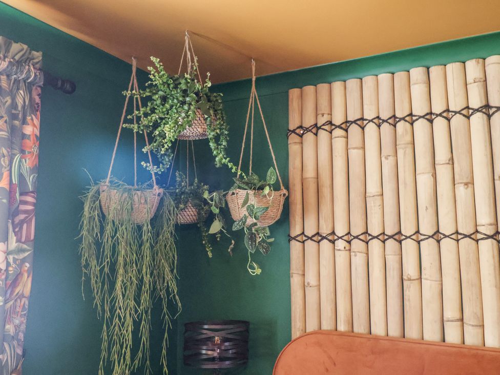 A living room with hanging plants and bamboo wall at Holly Farm in Colchester