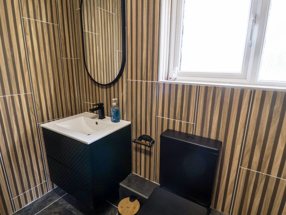 A bathroom with a sink, mirror, and toilet at Holly Farm in Colchester