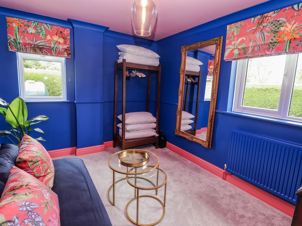 A bedroom with a couch and mirror at Holly Farm in Brantham