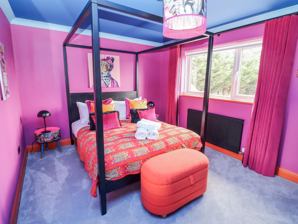 A bedroom with a four-poster bed and a window at Holly Farm in Brantham