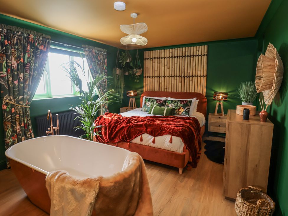 A bedroom with a bed and bathtub at Holly Farm in Brantham