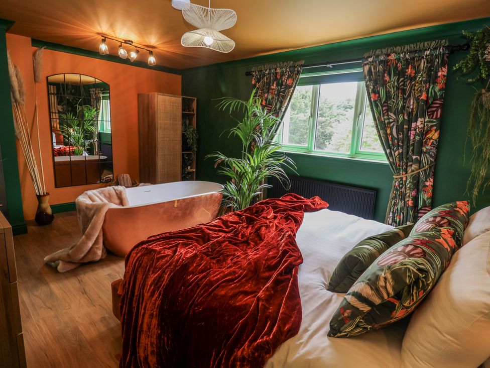 A bedroom with a bed and a bathtub at Holly Farm in Brantham