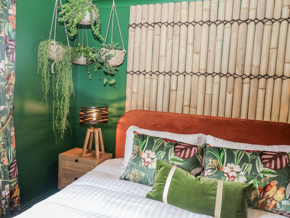 A bedroom with a bed and hanging plants at Holly Farm in Brantham