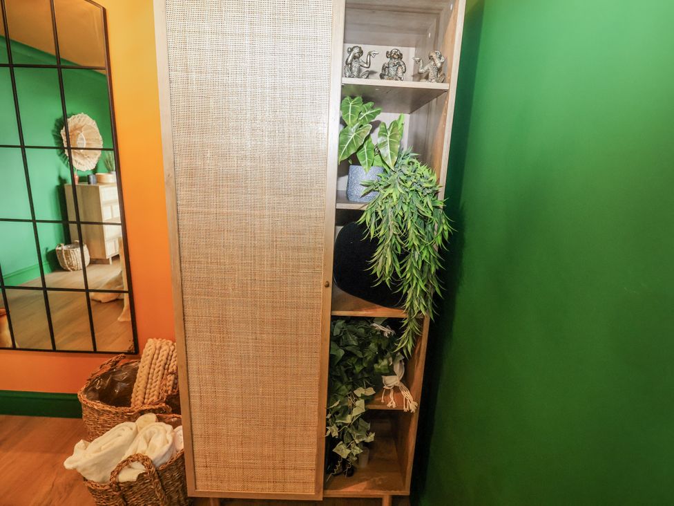 A cabinet with shelves containing plants and decorative elephants at Holly Farm in Brantham