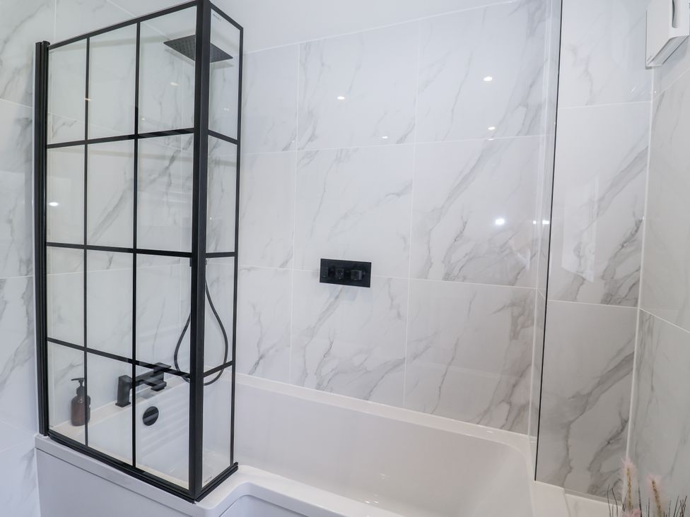 A bathroom with a bathtub and a shower enclosure at Holly Farm in Brantham