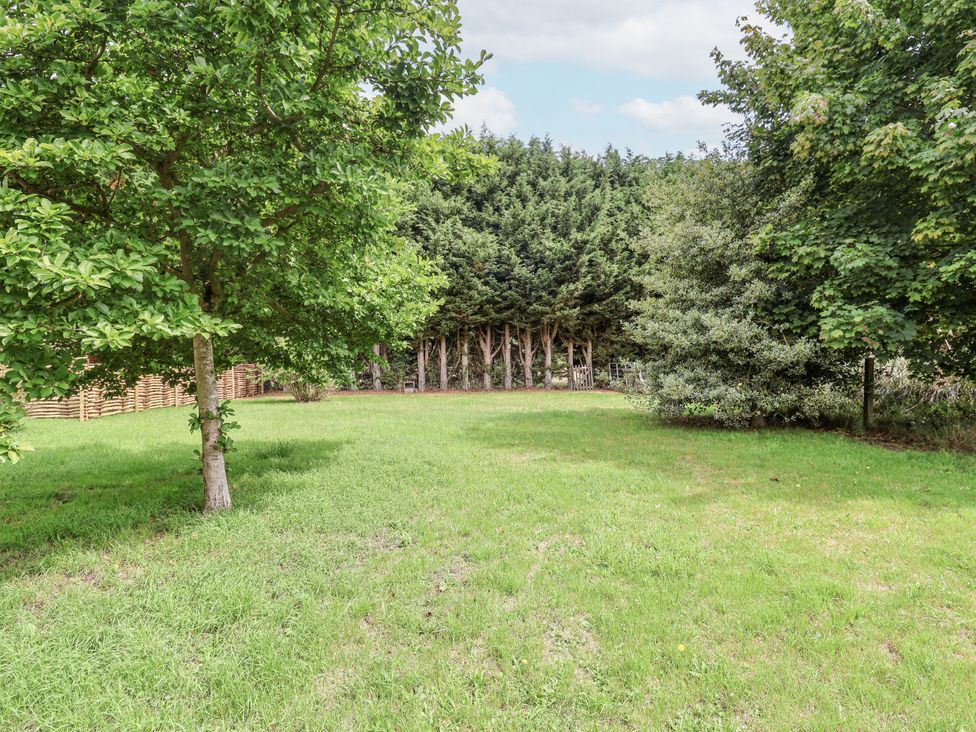 A garden with trees and grass at Holly Farm in Brantham