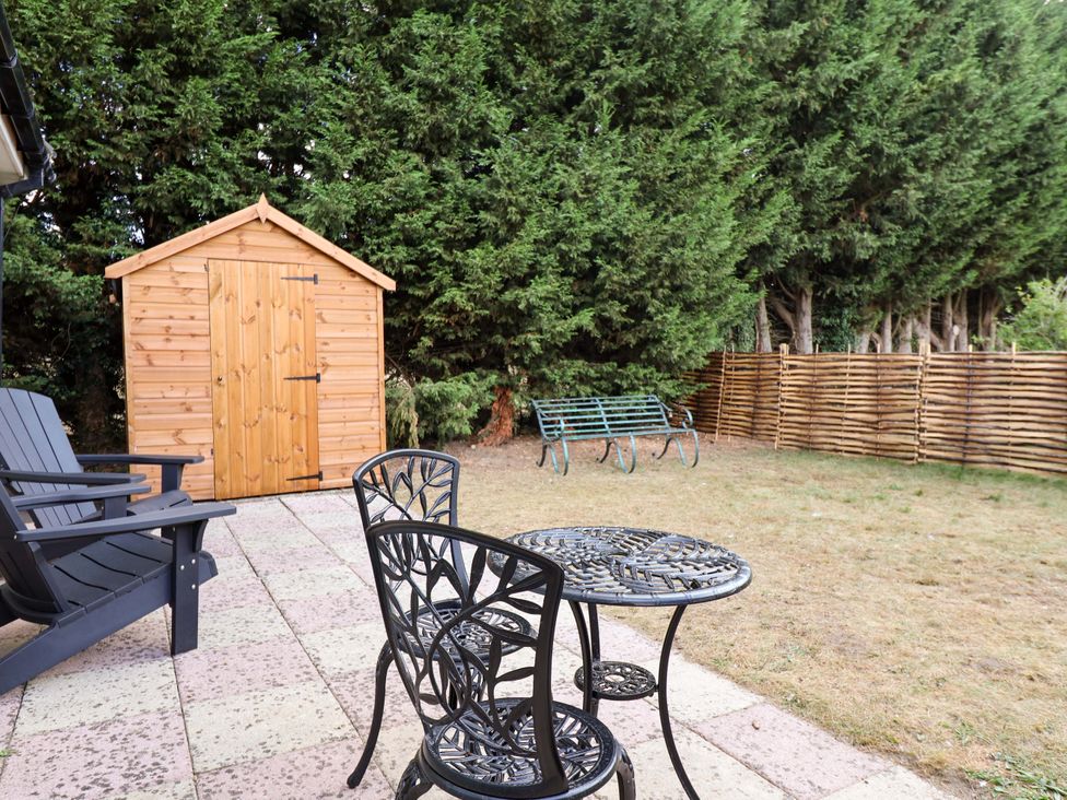 A garden with a wooden shed and furniture at Annexe East End near Brantham