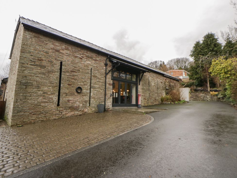 An exterior view of a stone building with windows and a cobblestone path at The Barn at Sunny Barn in Brecon