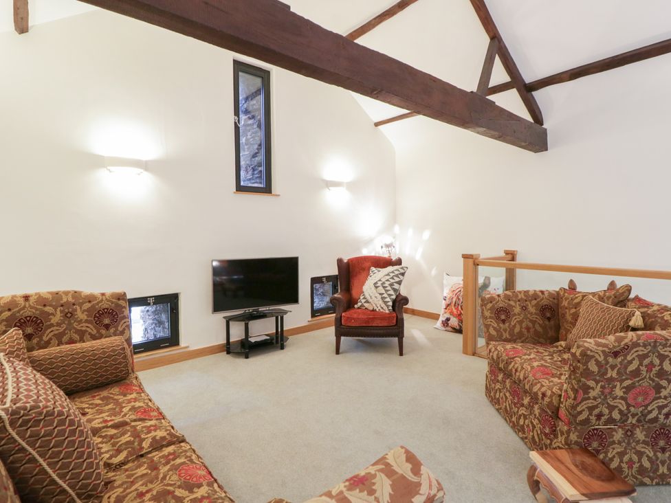 A living room with a sofa and television at The Barn at Sunny Barn in Brecon