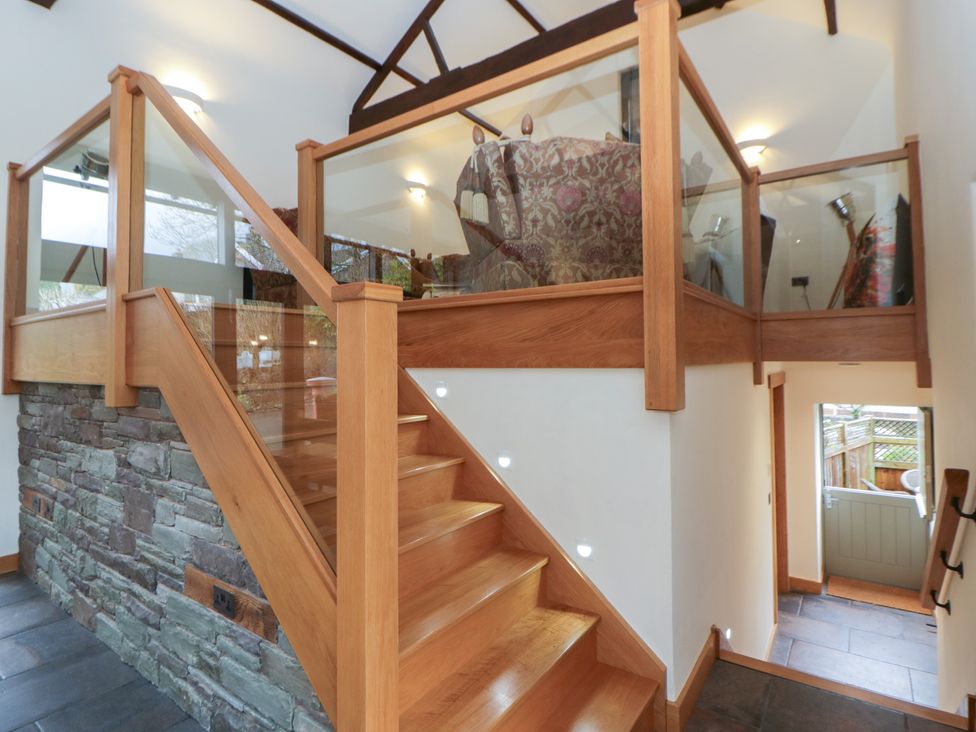 An entrance hall with staircase and glass railing at The Barn at Sunny Barn in Brecon